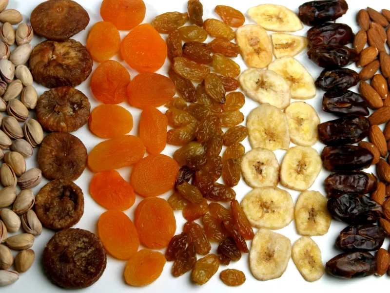 Dried apricots, figs, raisins, banana chips, dates, pistachios and almonds arranged in rows