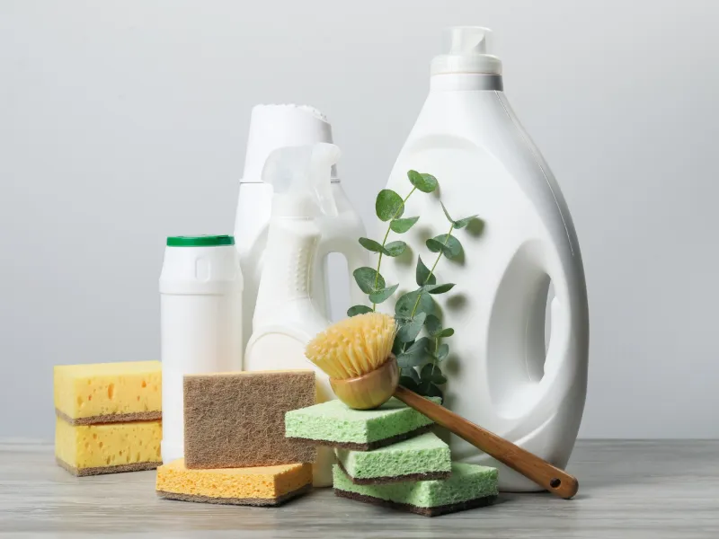 White household cleaning bottles with sponges and a brush