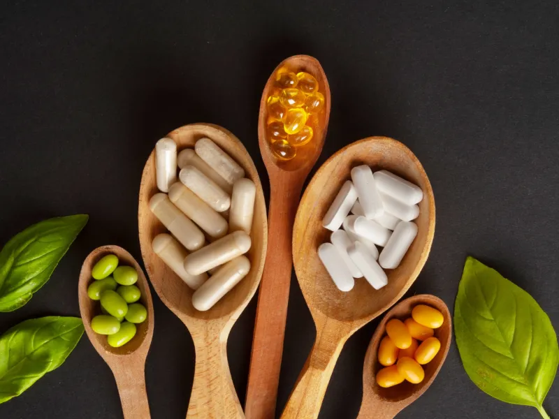 Supplement capsules and softgels on wooden spoons